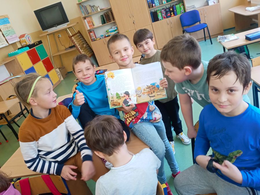 Uczniowie klasy IId czytają książkę o przygodach Fajniaków.