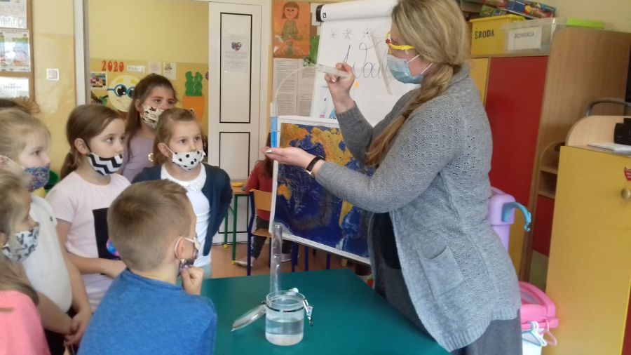 Żywioł Woda-nauczyciel prezentuje dzieciom eksperyment z wodą wykonany dwoma strzykawkami